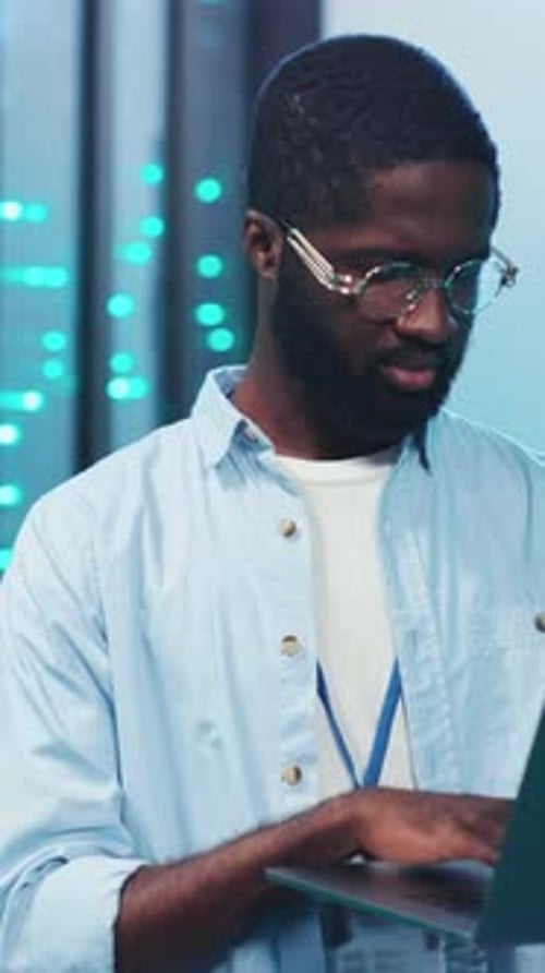 A Focused Young Professional is Seen Working Diligently on a Laptop in a Modern Dynamic Environment