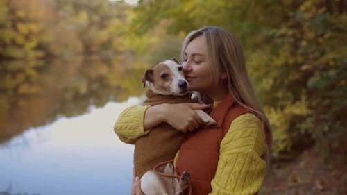 Portrait of a Smiling Young Woman Kissing a Dog in a Field