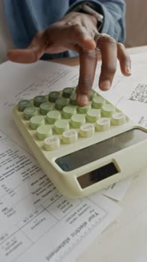 Black Man Analyzing Past Due Bill with Pen and Calculator at Home
