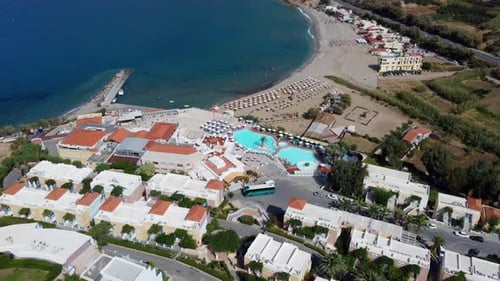 Drone flying over beach resort view to pool and strand in Greece on Crete, sunshades on strand