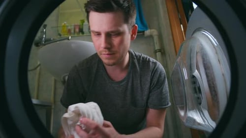Man Loading Clothes Into Washing Machine From Inside