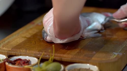 Nahaufnahme des Filetierens von frischem Fisch mit einem großen Messer auf einem Holzbrett