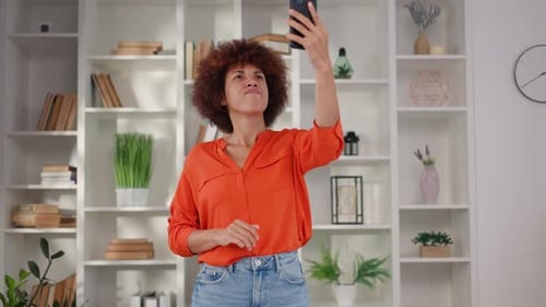 Woman Using Mobile Phone Indoors in Front of Bookshelf