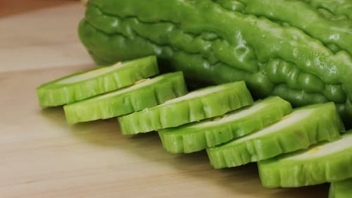 Une gourde amère, un légume souvent utilisé comme ingrédient en cuisine, est posée sur une table en bois.