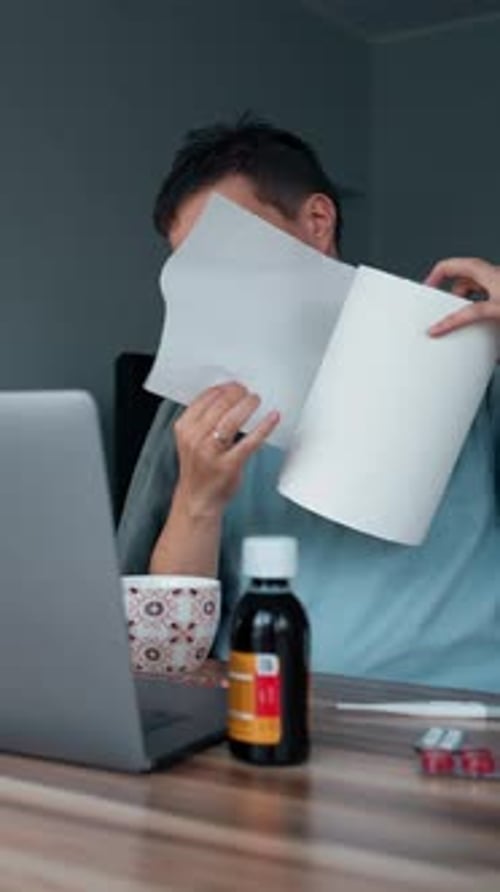 Vertical of Sick Freelancer Unrolls Napkins to Wipe Running Nose
