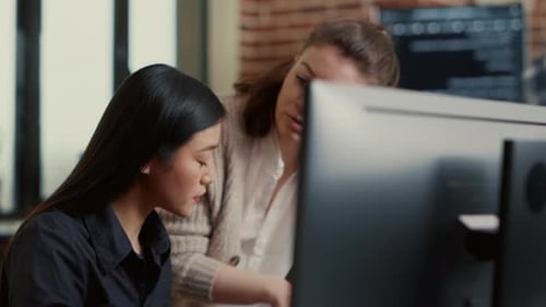 Software Development Team Reviews Coding Project at Development Workstation with Seated Workstation