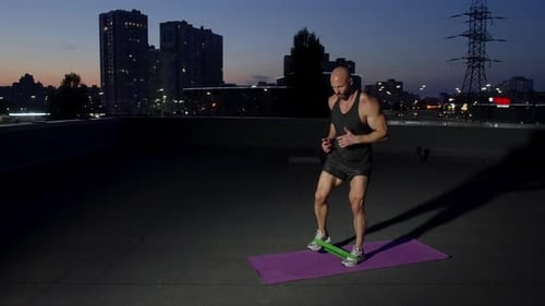 A Man with an Athletic Build is Doing Sports on a Rooftop in a Night City