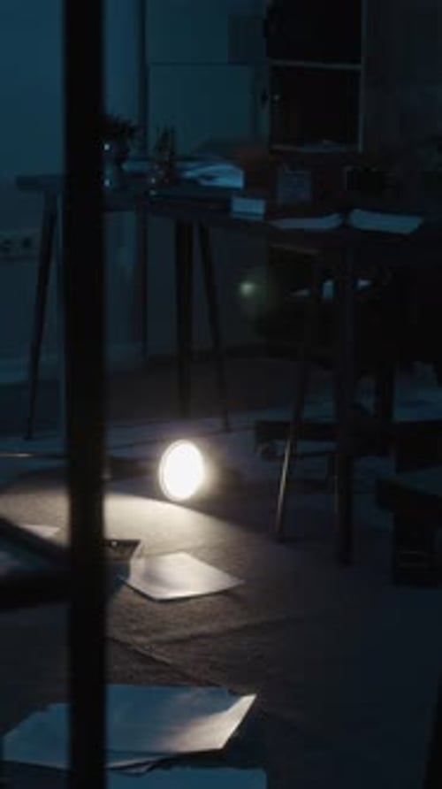Dimly Lit Office Scene Showing Scattered Papers on Floor and Fallen Desk Lamp