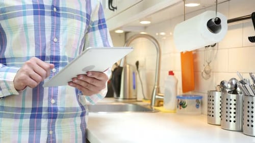 Adult Using Tablet in Bright White Kitchen