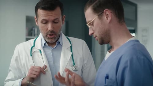 Two serious caucasian male doctors discussing over documents in medical clinic. Shot with RED helium