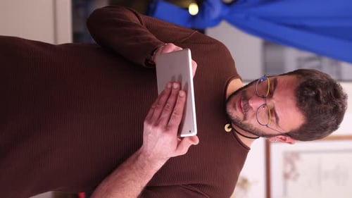 A cute man using a digital tablet. He is typing on a social network