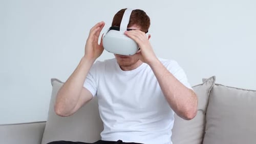 Man Putting On VR Headset On Couch