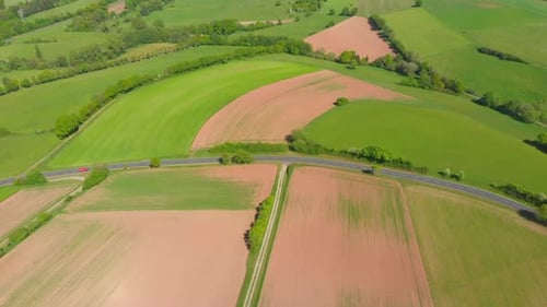 flying over rolling hills and fields in spring with lush green fields