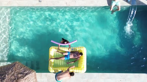 Friends at swimming pool aerial drone view of people that swim at pool floating over inflatable bed