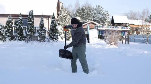 Young Man Shoveling Fresh Powdery Snow From a Residential Backyard Working to Clear a Path on a