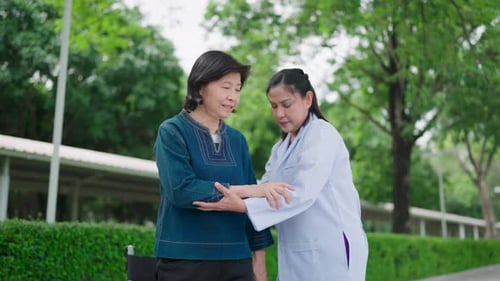 Medical Professional Helping Senior Woman Stretch Arm Outdoors