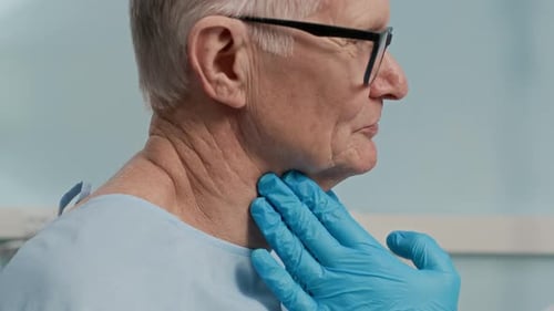 Hands of Doctor Examining Tonsils of Senior Patient in Clinic