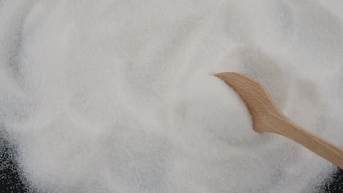 Spoon Scoops Up Pile of White Sugar