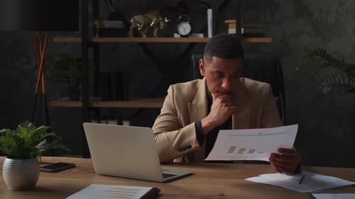 Man Analyzing Graphs in Modern Office