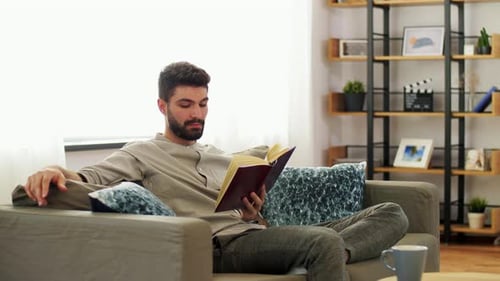 Bearded Man Reading a Book on the Sofa