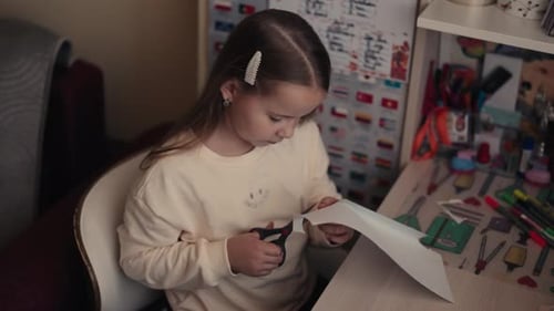 Young Girl Cutting Paper with Scissors at Desk Creative Arts and Crafts Activity