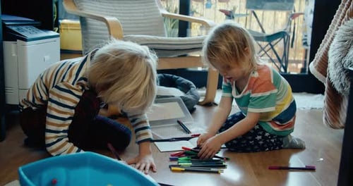 Two Children Drawing Together at Home on Floor