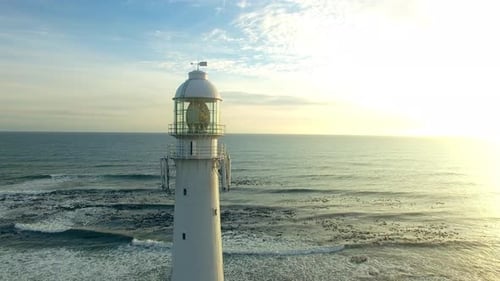 Vista aérea, Zumbido y faro en el océano en un cielo al atardecer o al amanecer