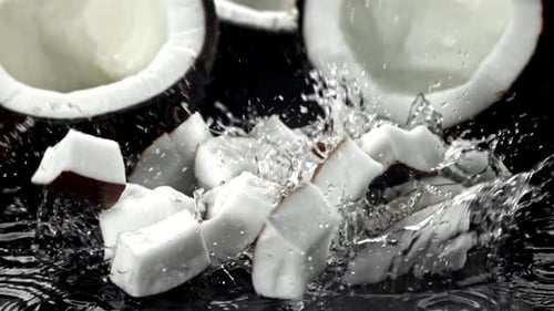 Coconut pieces falling into dark water with splash