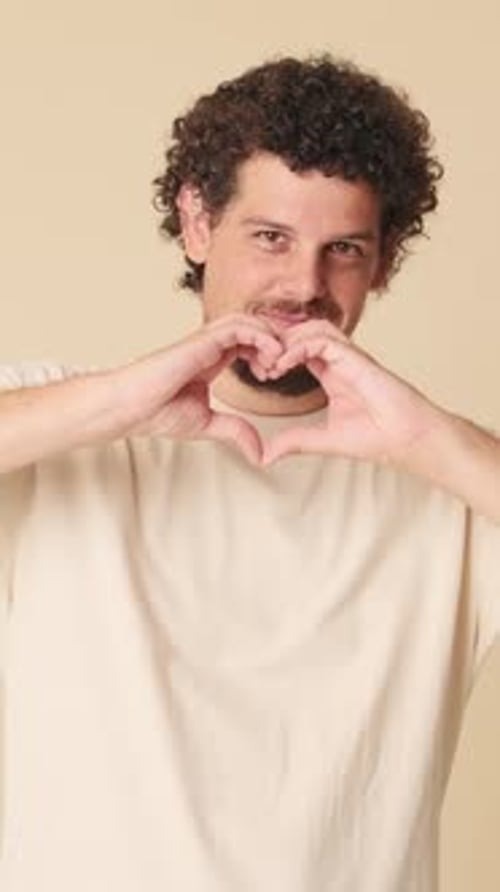 Man Forms Heart Shape with Hands Smiling