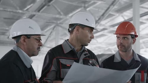 Construction Workers Reviewing Blueprints Onsite Indoors