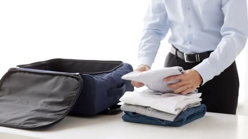 Businessman carefully packing clothes for business trip in hotel room