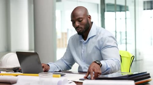 Architect, engineer, construction manager typing at desk while checking his phone
