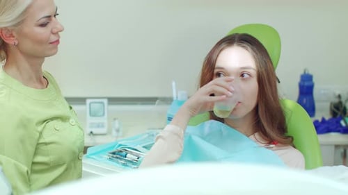 Young woman gargling mouth after stomatology treatment in dentist chair