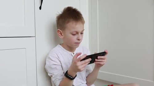 Boy Playing Game on Mobile Phone Indoors