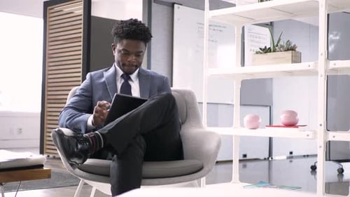 Young african american businessman uses digital tablet in modern office lobby