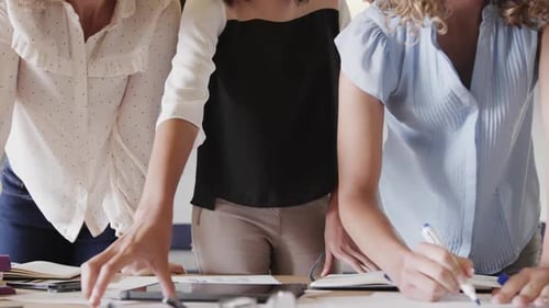Midsection of diverse female colleagues in discussion in casual office meeting, slow motion