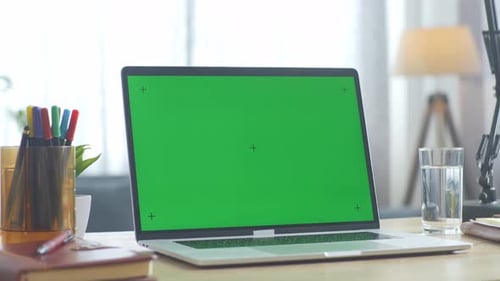 Close up of a mock up green screen laptop on a desk with notebook at the office