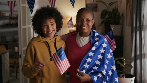 Portrait of Joyful Mother and Son with US Flags in Decorated Living Room