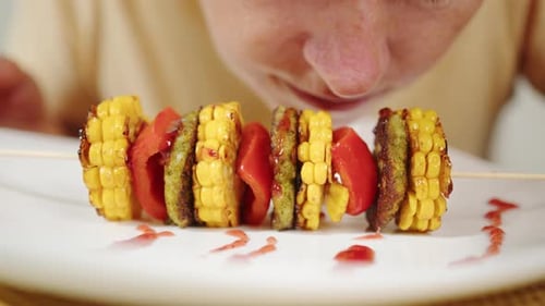 Vegan woman tasting meal of vegetable barbecue on skewer.