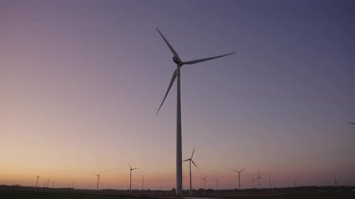 Wind Turbine in a large wind farm. Large wind turbine in field against sunset on horizon. Renewable