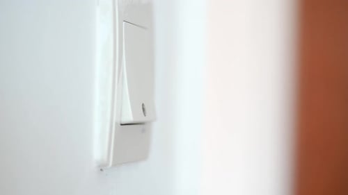 Finger Pushing a Light Switch on a Wall