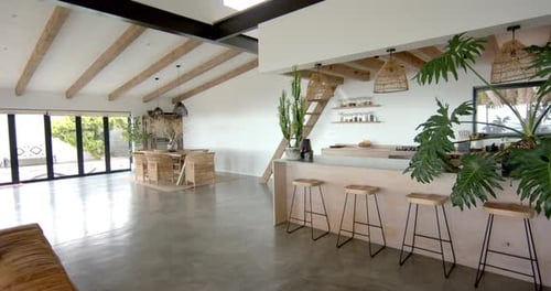 Modern kitchen and living area with wooden beams and bar stools in home
