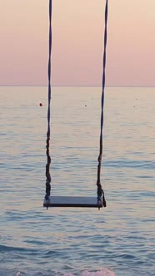 Leere Schaukel über dem Meer bei Sonnenuntergang, die zu friedlicher Kontemplation und Entspannung einlädt