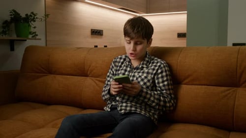 Boy Using Smartphone on Sofa at Home