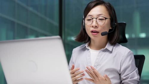 Business Woman Talking on Headset in Front of Laptop