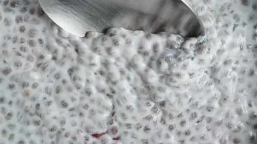 Spoon Stirring Creamy Chia Seed Pudding with Strawberries