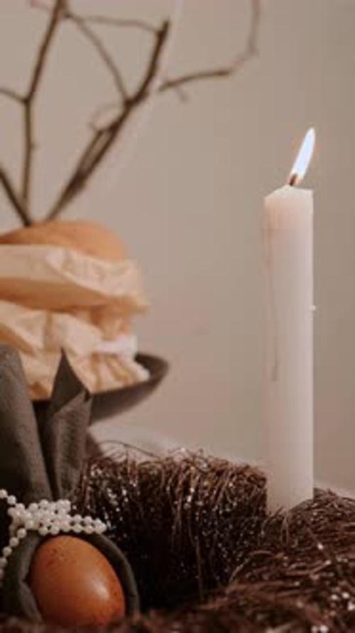 Nahaufnahme einer langsam ausbrennenden Kerze auf einem Ostertisch mit Kucheneiern in einem Tablett, dekorativer Kranz