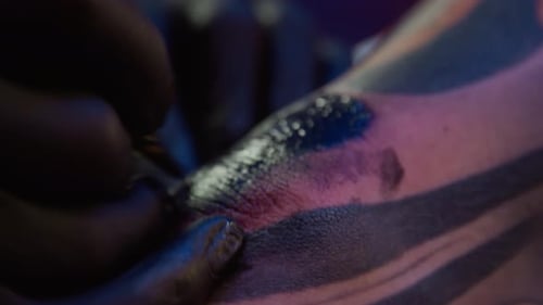 Hands of Tattooist Applying Ink with Tattoo Machine on Customers Skin
