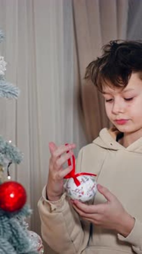 Lovely teenager boy decorating Christmas tree in the house.