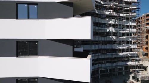 Baufortschritt eines modernen Wohnhauses mit Gerüst in einem belebten Stadtgebiet